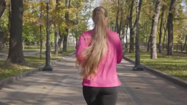 身穿粉色运动服的白人女人的画像 她用智能手机送出了飞吻 然后开始奔跑 女赛跑选手在室外晨练 体育概念 — 图库视频影像