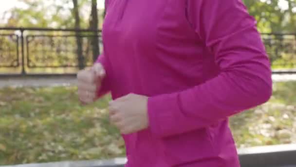 在秋天的公园里 一个穿着运动服 留着长尾巴的年轻的无法辨认的白人女孩的特写 女赛跑选手在室外晨练 体育概念 — 图库视频影像