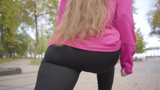Close-up of female Caucasian legs doing walking lunges. Young sportswoman training in the autumn park in the morning. Sports concept. — ストック動画