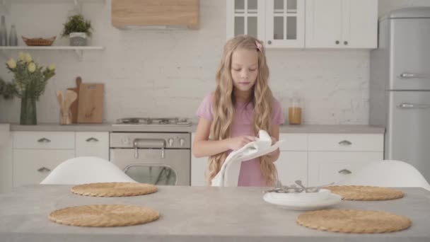 年轻而严肃的白人少女穿着粉色衣服 在现代厨房里擦盘子 勤奋的金发少女帮她的家人做家务活 — 图库视频影像