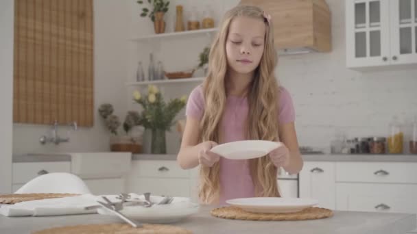 身穿粉红衣服的金发白人少女端上来 微笑着 勤奋的青少年在现代厨房做家务活 — 图库视频影像