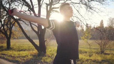 Sonbahar parkında günbatımında yakışıklı beyaz bir çocuktan ip atlama egzersizi. Spor giyimi eğitimi alan genç bir adam. Sağlıklı yaşam tarzı spor konsepti.