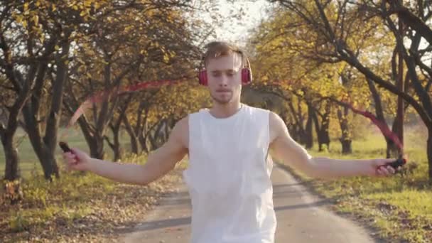 Ung Vit Pojke Hörlurar Och Sportkläder Hopprep Höstparken Idrottsutövare Tränar — Stockvideo