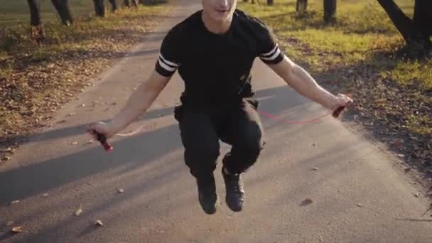 Homem Bonito Caucasiano Jovem Sportswear Preto Pulando Agachamentos Com Corda — Vídeo de Stock