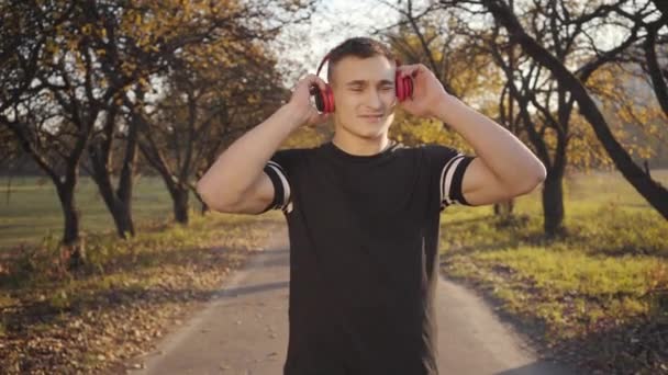Ein Gutaussehender Kaukasischer Junge Schwarzer Sportbekleidung Setzt Sich Kopfhörer Auf — Stockvideo