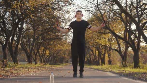 Retrato Jovem Esportista Caucasiano Fones Ouvido Sportswear Preto Pulando Corda — Vídeo de Stock