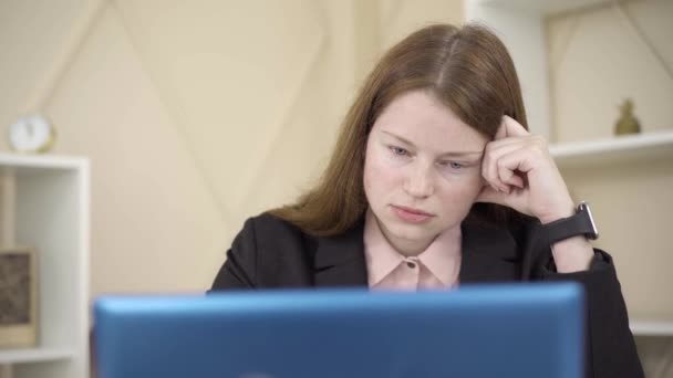 Face de perto de uma jovem exausta a trabalhar online. Retrato da ruiva cansada Freelancer caucasiano usando laptop em casa. Conceito de trabalho remoto, freelance, estilo de vida, cansaço . — Vídeo de Stock