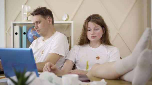 Relaxed redhead woman checking empty wallet with dissatisfied facial expression. Portrait of young female and male freelancers working online using laptops. Remote work, income, lifestyle. — Stock Video