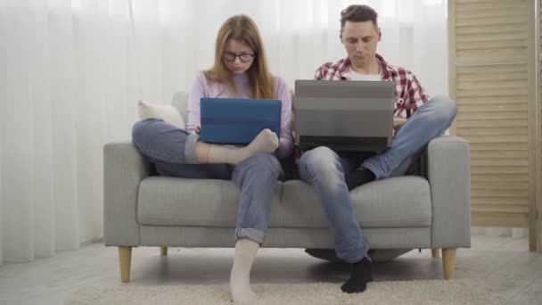 백인 밀레니엄 남자와 여자는 노트북을 폐쇄하고, 한숨을 쉬고, 하이파이브를 합니다. 젊은 백인 남성 과 여성 프리랜서들 이 집에서 휴식을 취하고 있습니다. 무선으로 일하고 생활하는 일. — 비디오