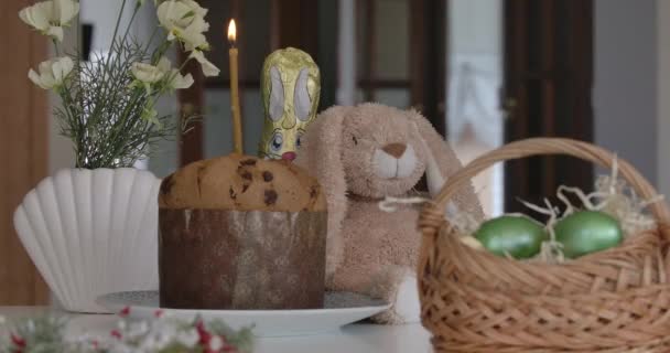 Vela que sopla en el pan de Pascua Paska. Primer plano de los artículos tradicionales ucranianos religiosos sobre la mesa. Cesta con huevos pintados de colores y bollo dulce. Religión, concepto de celebración . — Vídeos de Stock