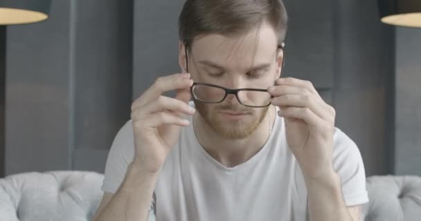 Retrato de cerca del hombre caucásico cansado quitándose las gafas y frotando las sienes. Guapo agotado morena chico teniendo estrés. Dolor de cabeza, tensión, exceso de trabajo. Sede del cine 4k ProRes . — Vídeos de Stock