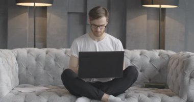 Laptop klavyesinde daktilo kullanan yakışıklı bir adamın portresi. İnternette sörf yapan ya da sosyal medyayı içeride kullanan Kafkasyalı esmer adamın ön görüntüsü. Cihaz bağımlılığı. Sinema 4k ProRes Merkezi.