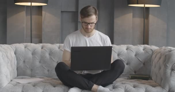 Retrato del joven hombre guapo escribiendo en el teclado del ordenador portátil. Vista frontal de tipo caucásico concentrado morena navegar por Internet o el uso de las redes sociales en el interior. Adicción al dispositivo. Sede del cine 4k ProRes . — Vídeo de stock