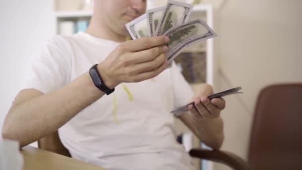 Mannelijke blanke handen die dollars tellen. Onherkenbare jongeman in vies T-shirt berekent inkomsten uit freelance. Rijkdom, levensstijl, werk op afstand, rijkdom, geld. — Stockvideo