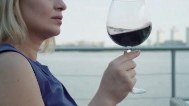 Doymuş iş kadınlarının aşırı yakın çekimi açık hava restoranında pahalı kırmızı şarap tadıyor. Yüzünde gülümseyen beyaz bir kadının açık havada alkol kokusu ve içmesi..