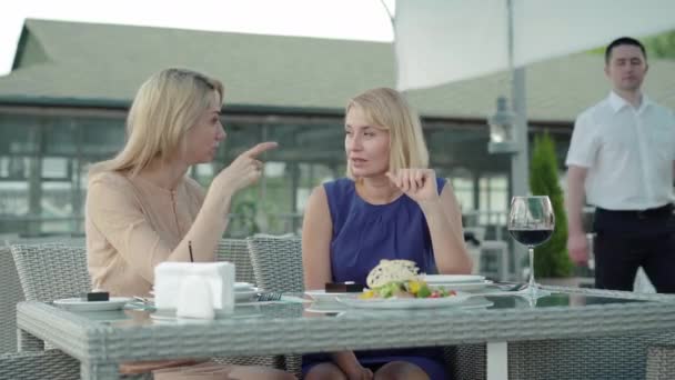 Mujeres ricas positivas hablando en la mesa como camarera trayendo pescado frito. Retrato de clientes mujeres ricas descansando en un restaurante al aire libre. Negocios, industria alimentaria, ocio, estilo de vida, servicio . — Vídeos de Stock