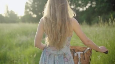 Kamera, genç esmer, beyaz bir kadının güneşli çayırlarda bisiklet sürüşünü izliyor. Sıska bir kızın arka plan portresi parkta geziniyor. Yaşam tarzı, mutluluk, sükunet.