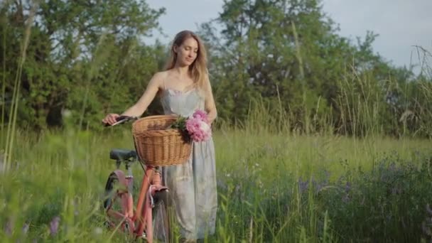 Giovane donna in abito retrò a piedi con elegante bicicletta lungo il prato nel parco cittadino. Fotocamera segue caucasico bruna ragazza passeggiando all'aperto in soleggiata estate fine settimana giorno. — Video Stock