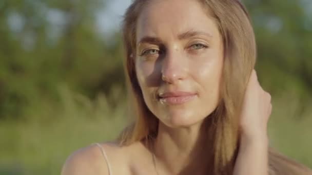 Primer plano retrato de morena mujer positiva sonriendo a la cámara. Hermosa cara de encantadora hermosa chica caucásica posando al aire libre en el soleado día de verano. Belleza, elegancia, ocio, felicidad . — Vídeo de stock