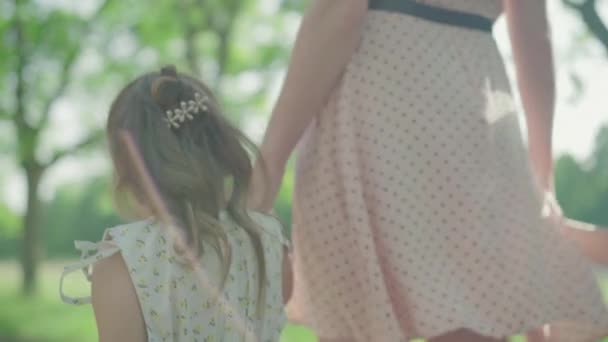 Vrolijke kleine jongen en meisje die weglopen van moeder in zonnestralen in het zomerpark. Onherkenbare jonge blanke vrouw wandelen buiten met zoon en dochter. Moederschap, vreugde, levensstijl. — Stockvideo