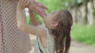 Tanımlanamayan anne gülümseyen beyaz bir kızın yüzüne dokunuyor. Mutlu kızın portresi anne babaya bakıp gülümsüyor. Eğlence, çocukluk, aşk, eğlence, yaşam tarzı..