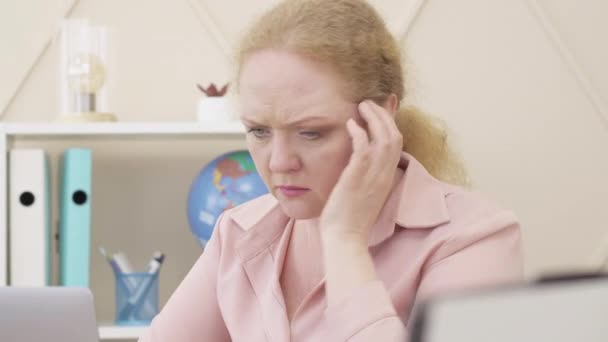 Cara de cerca de la mujer mayor caucásica desesperada sosteniendo la cabeza con la mano como mirando la pantalla del ordenador portátil. Dificultades del trabajo remoto en el bloqueo pandémico de Covid-19 . — Vídeos de Stock