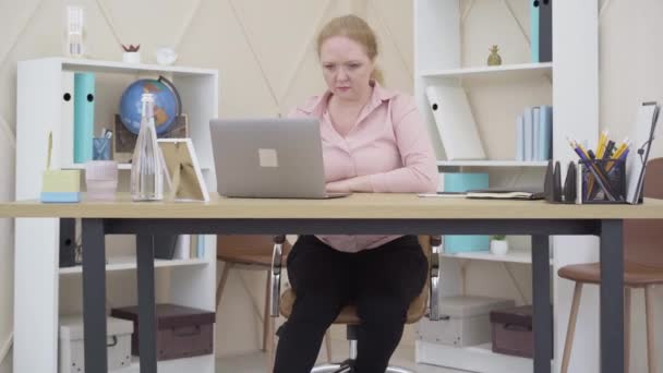 Kamera se blíží k ženě, která sedí u stolu s laptopem a dělá vítězné gesto. Portrét spokojené kavkazské starší dámy vyhrávat v on-line hře nebo podnikatelka dělat on-line obchod. — Stock video