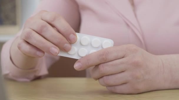 Kvinnliga kaukasiska händer tar piller från blister. Oigenkännlig äldre kvinna som använder mediciner mot sjukdom. Behandling, medicin, apotek, smärtstillande medel, vitaminer. — Stockvideo