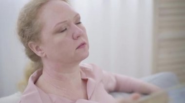 El sallayan yorgun kadının yakın plan yüzü. Kafkasyalı bir kadının portresi sıcak basması yüzünden acı çekiyor. Menopoz belirtileri, orgazm, yaşlanma.
