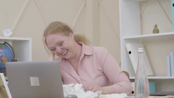 Portrait de femme âgée riant à haute voix alors qu'elle était assise à la table avec une pile de tissus usagés. Stressé dame caucasienne ayant des sautes d'humeur. Concept d'instabilité émotionnelle pendant les changements climatiques. — Video