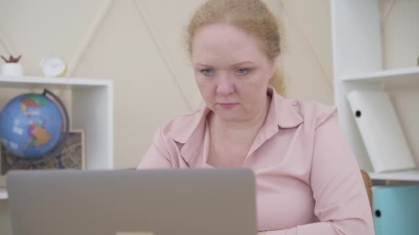 Mulher ruiva sênior fechando laptop e olhando para a câmera. Senhora expressando emoções opostas, rindo e chorando. Estilo de vida, mudanças climáticas, instabilidade emocional . — Vídeo de Stock