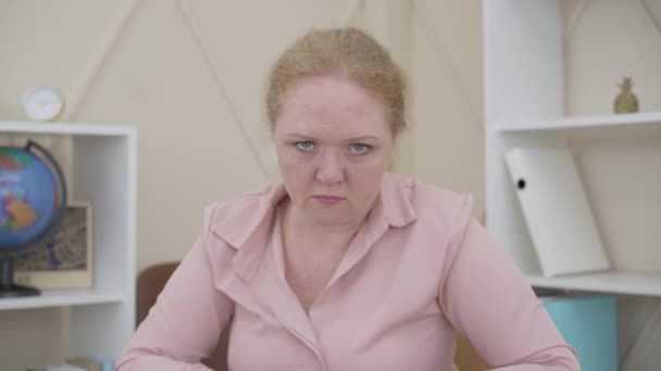 Porträt einer wütenden Seniorin, die mit der Faust auf einen Tisch schlägt. Wütende Kaukasierin, die ihren Hass ausdrückt, während sie in die Kamera schaut. Schlechte Gefühle, Wut, Wahnsinn. — Stockvideo