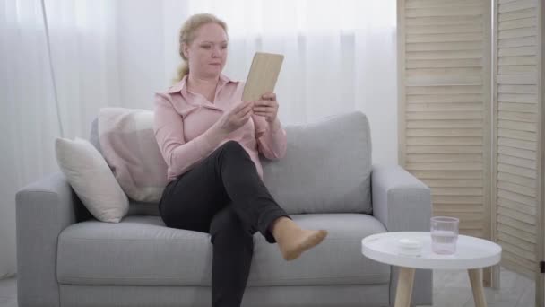 Femme âgée prenant miroir de main et vérifier le maquillage. Portrait large de retraitée caucasienne sérieuse prenant soin du visage à l'intérieur. Vieillissement, féminité, beauté. — Video