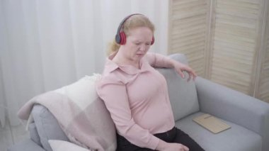 Kulaklıkla aktif müzik dinleyen son sınıf öğrencisi olumlu bir kadın. Beyaz kadın emeklinin portresi evde boş vakitlerin tadını çıkarıyor. Yaşam tarzı, hobi, rahatlama, keyif..