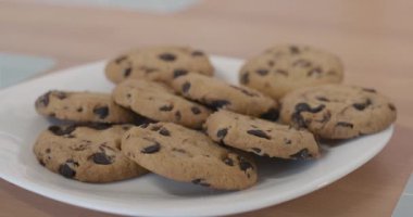 Masanın üzerinde bisküviler dururken, küçük beyaz çocuğun eli bir kurabiyeyi alırken son derece yakın plan bir tabak. Tanınmayan bir çocuk evde tatlı pastaneyle öğle yemeği yiyor..