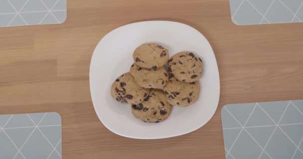 Κάτοψη του πιάτου με τα μπισκότα στο τραπέζι με τα χέρια των παιδιών να παίρνουν γλυκά μπισκότα αφήνοντας το άδειο. Αγνώριστα λευκά παιδιά που τρώνε ανθυγιεινά νόστιμα τρόφιμα. — Αρχείο Βίντεο