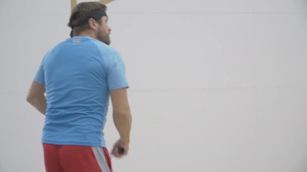 Sidovy över vuxen skäggig man spelar squash i gymmet. Mellanskott porträtt av kaukasiska idrottare träning sport spel inomhus. Koncentrerad brunett kille tränar i sportklubb. — Stockvideo
