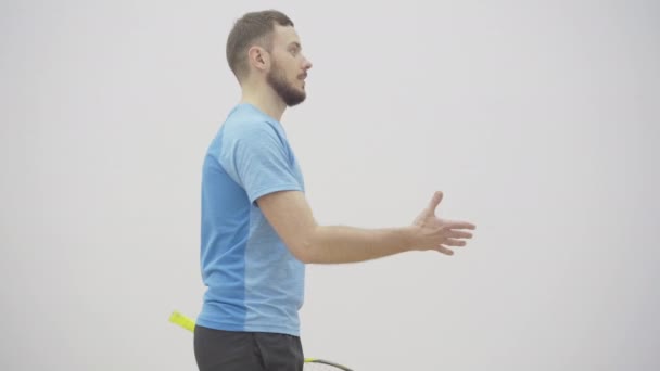 Jeune sportif en forme accueillant client dans la salle de gym. Portrait d'homme blanc beau confiant avec raquette de squash serrant la main avec chubby mi-adulte gars sur cour intérieure. — Video