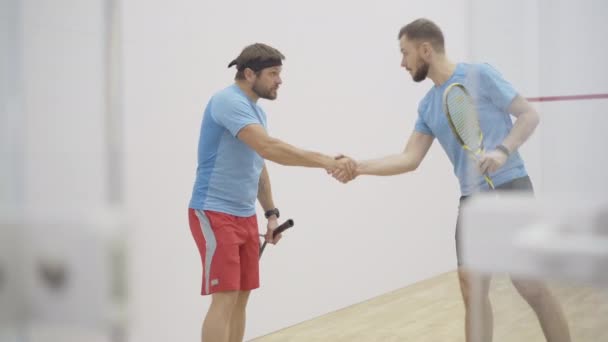 Kendinden emin, orta yaşlı bir adam kişisel antrenörüne veda ediyor ve kapalı sahadan ayrılıyor. Beyaz adamın portresi spor giyim antrenmanında spor salonunda squash oynuyor.. — Stok video