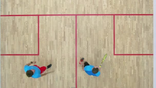 Vue du dessus de deux sportifs serrant la main après le match de squash et partant. Hommes caucasiens confiants concourant dans la salle de gym sur le terrain intérieur. Concept de sport de compétition. — Video