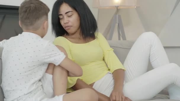 Retrato de una encantadora mujer afroamericana hablando con su pequeño hijo por la noche. Joven madre pasando el fin de semana con el niño en casa. Feliz ocio de la familia amistosa en el interior. — Vídeo de stock