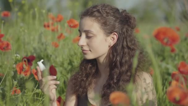 Gros plan d'une jeune femme mince utilisant un spray allergique sur un pré fleuri et souriant. Portrait de dame allergique caucasienne appréciant le repos sur le champ de coquelicots rouges grâce à la médication. — Video
