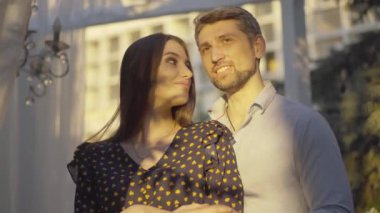 Mutlu çift gün batımına bakıyor ve konuşuyor. Neşeli beyaz erkek ve kadının güneş ışığında sarılıp sohbet edişinin portresi. Orta yaşlı erkek arkadaş ve genç kız arkadaş açık havada çıkıyorlar..