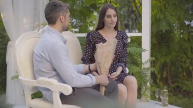 Kafkas erkeğinin mutlu esmer kadına bir buket çiçek vermesi. Güzel mutlu kız arkadaşın portresi erkek arkadaşından yaz buluşmasında güller alıyor..