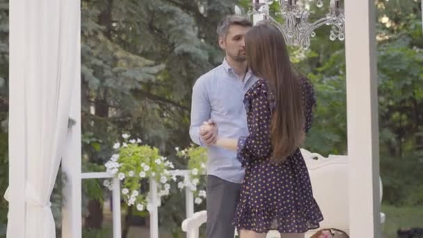 Портрет щасливої пари, що танцює в романтичному павільйоні на вулиці. Любив кавказьких чоловіків і жінок, які зустрічалися влітку. Посміхаючись, дорослий хлопець і молода дівчина насолоджуються вихідними.. — стокове відео