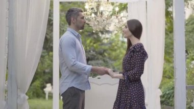 Gülümseyen, sevgi dolu bir adamın güzel genç bir bayanın elini tutması ve konuşması. Kafkas erkek arkadaşının romantik köşkte duygularını itiraf edişinin portresi. Aşk ve aşk kavramı.