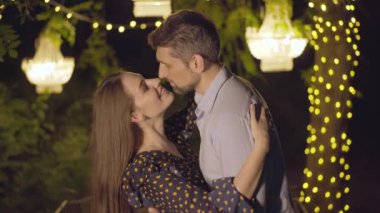 Yazın açık havada gülümseyen romantik erkek ve kadın. Sevgili orta yaşlı koca ve genç eşin birbirine sevgiyle bakan konuşmalarının ve gülümsemesinin yakın plan portresi..