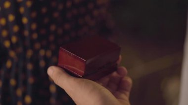 Beyaz erkeklerin yakın plan çekimleri, alyanslı kutuları açıyor. Tanınmayan bir adam yaz gecesi dışarıda bir kadına evlenme teklif ediyor. Romantik nişan.