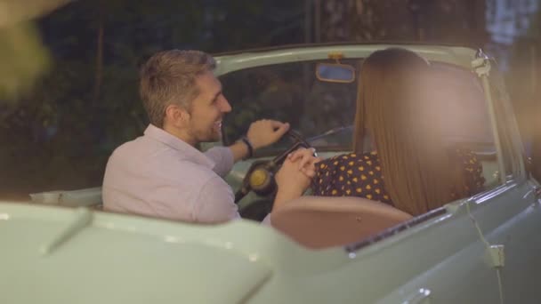 Погляд на щасливу пару, яка сидить у машині ретро, тримаючись за руки і розмовляючи. Любить кавказьких чоловіків і жінок, які зустрічаються в романтичному місці на вулиці. Портрет щасливого хлопця й дівчини.. — стокове відео