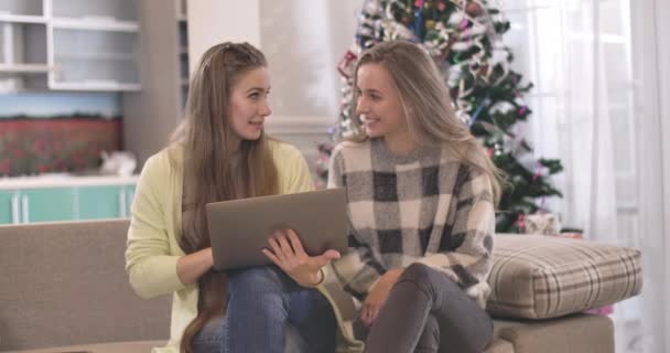 Две позитивные белые женщины делают покупки онлайн в канун Рождества. Портрет радостных расслабленных друзей, которые сидят в интернете на ноутбуке в канун Нового года. Штаб-квартира кинотеатра 4k ProRes. — стоковое видео